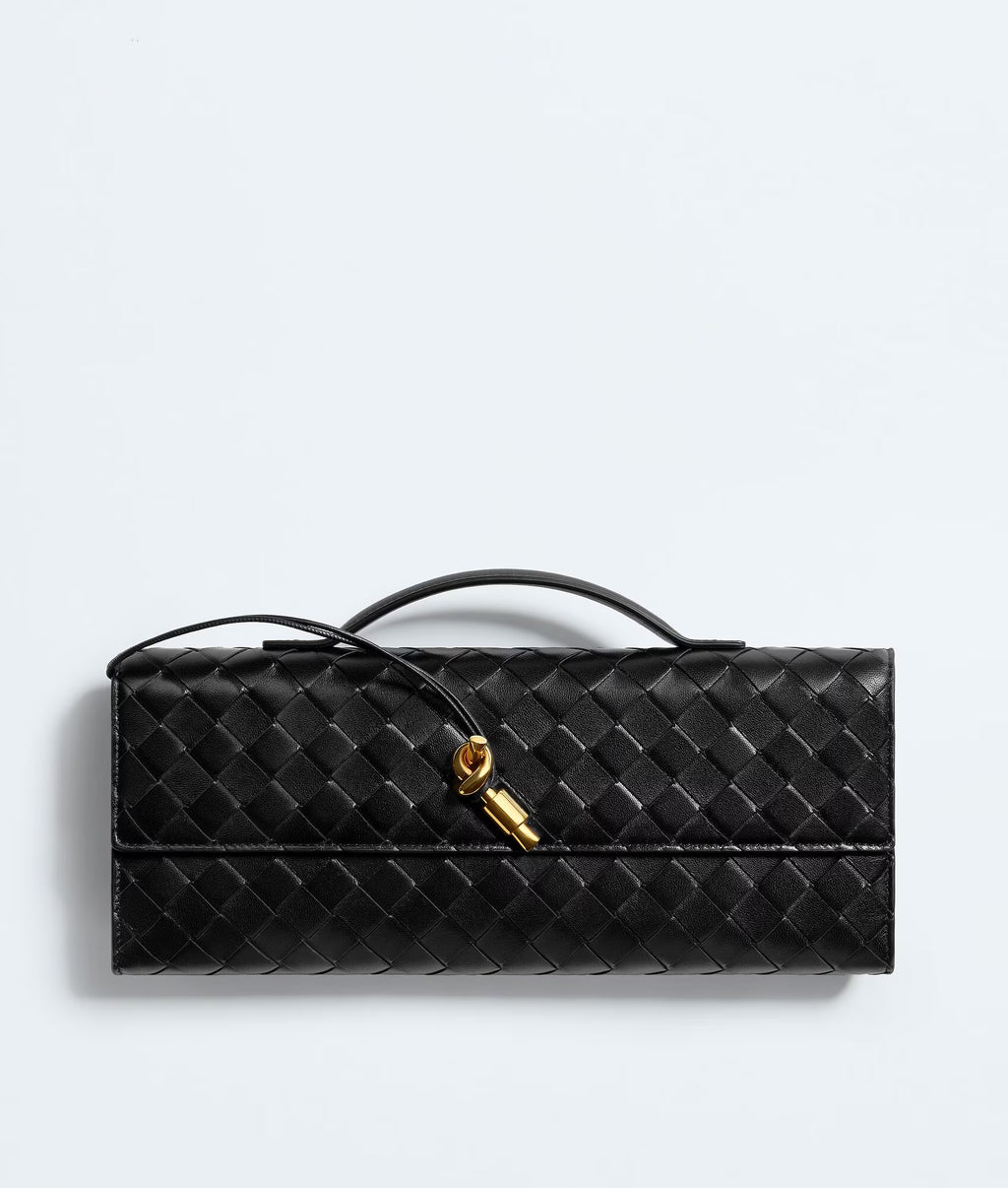 Black woven handbag with gold clasp on a light gray background