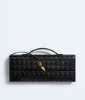 Black woven handbag with gold clasp on a light gray background