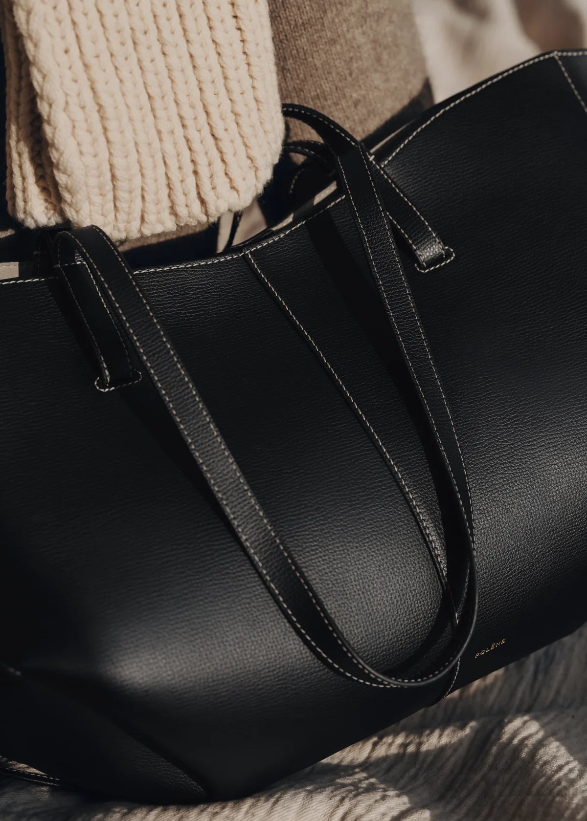 Black leather tote bag on a wooden surface with a blurred background