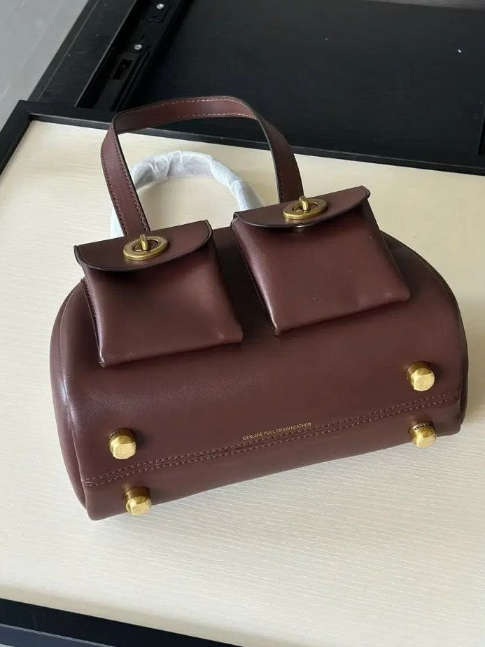 Brown handbag with gold accents on a display stand
