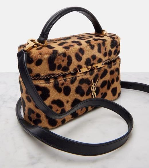 Leopard print handbag with black handle and strap on a white background