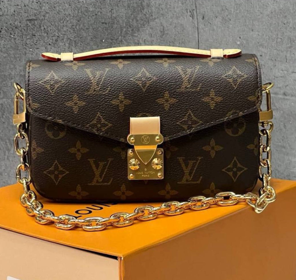 Louis Vuitton handbag with monogram pattern on a box with branding and accessories.